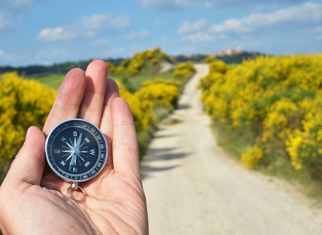 Compass in the hand against rural road