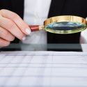 Businesswoman Looking At Document Through Magnifying Glass